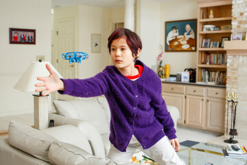 A boy in purple cardigan reaches out to play with hovering toy inside