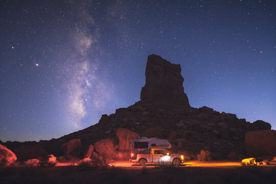 A small pickup RV is on a camping spot under the Milky Way