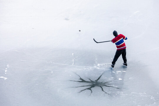 From above unrecognizable hockey player shooting puck on ice in Canada