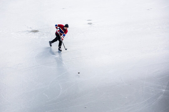 Hockey player skating and shooting puck on ice playing pond hockey - Powered by Adobe
