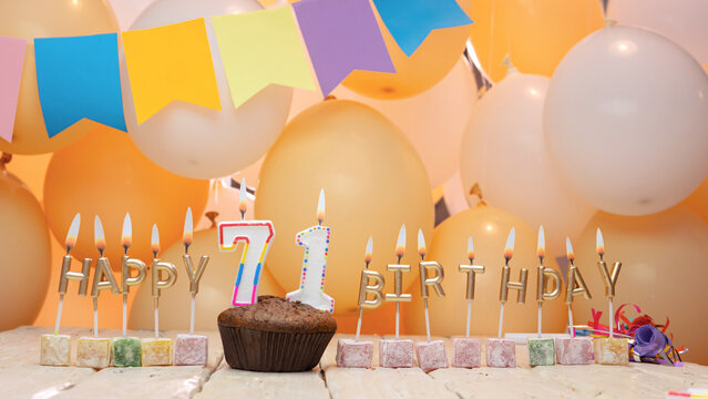 Happy birthday greetings for 71 years from gold letters of candles burning against the background of mine space balloons. Beautiful birthday card with a muffin for seventy-one years