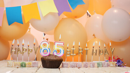 Happy birthday greetings for 85 years from gold letters of candles burning against the background...