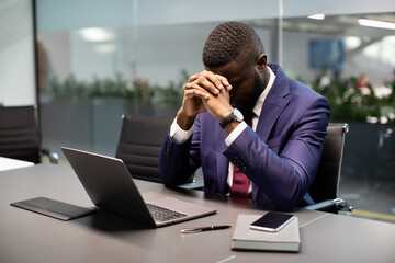 Frustrated black businessman sitting in front of laptop