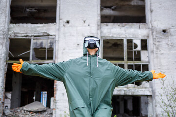 A dosimetrist scientist in protective clothing and a gas mask checks the level of radioactive...