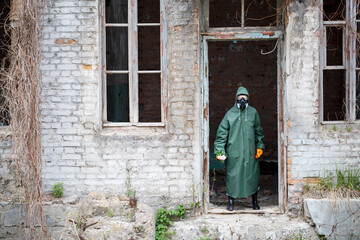 A dosimetrist scientist in protective clothing and a gas mask examines the danger zone. Close-up. flower in hands
