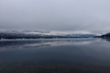 Scenic view of Bohinj lake in Slovenia with low level clouds above the lake and a reflection in the water