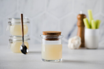 Bone broth soup in glass storage jars with spices and celery on the background. The concept of healthy eating.