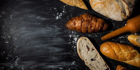 bakery - baked bread and pastry products with flour on black background. banner copy space