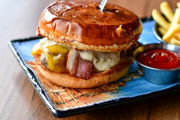 Delicious Beef  Burger  with bacon, cheddar ,egg  and home made french fries from organic potatoes on wooden table 