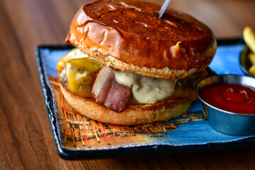 Delicious Beef  Burger  with bacon, cheddar ,egg  and home made french fries from organic potatoes on wooden table 