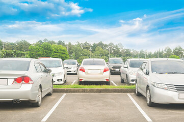 Car parking in asphalt parking lot and empty space parking with trees, white cloud and blue sky background.