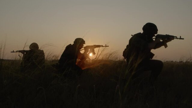 Combat training of armed snipers running and aiming at enemies on field.