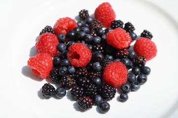 Fruits des bois, myrtilles sauvages, framboises et mûres dans une assiette