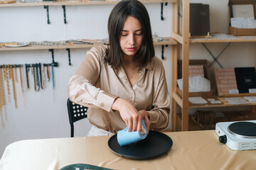 Portrait of focused young woman artisan taking out beautiful white piece of author candle of...