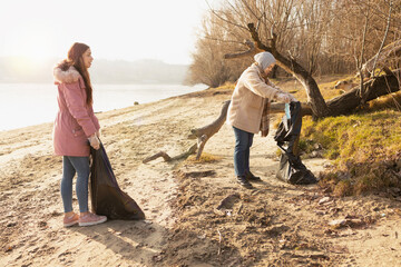 Two volunteers cleaning up the trash from a riverside
