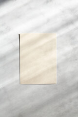 Blank paper sheet cards with sunlight shadows on stone background. Mockup scene with contrasting shadows