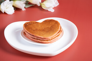 Creative breakfast for Valentine's Day. Heart shaped pancakes on a red background.