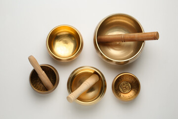 Golden singing bowls and mallets on white background, flat lay