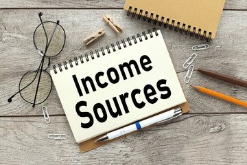 INCOME SOURCES notebook on a wooden table