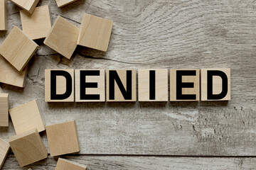 Denied text on wooden blocks on a working wooden table.