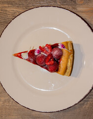Red fruit cheesecake slice on wooden background, red fruit dessert.