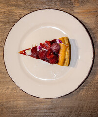 Red fruit cheesecake slice on wooden background, red fruit dessert.