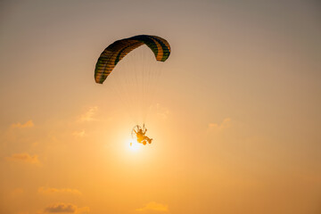 Silhouette paraglider under play paramotor extreme sport, transportation fly on sky with sunlight...
