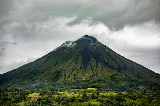 Grassy volcano against cloudy sky