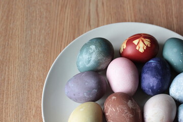 Fototapeta na wymiar blue, red , brown Easter eggs in ceramic dish on wooden background.