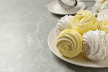 Delicious white and yellow marshmallows on grey marble table. Space for text