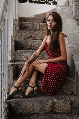 Fototapeta premium attractive brunette girl with a sexy figure poses on a stone staircase on the steps in an old European city
