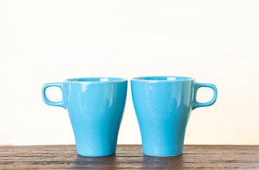 Two aqua blue cups on wood table with isolate white background.