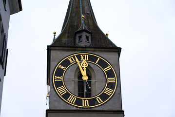 Protestant clock tower of church St. Peter with gray sky background on a winter day. Photo taken February 1st, 2022, Zurich, Switzerland.