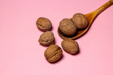 Whole walnuts on a pink background. Nutritious fruits.