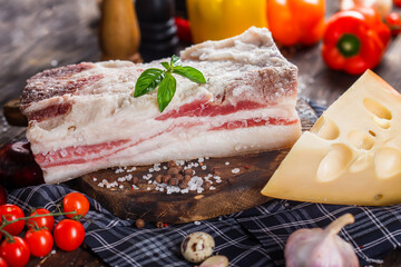 fresh lard pork lard with salt, on a kitchen cutting board, hard cheese, cherry tomatoes and...