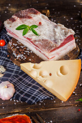 fresh lard pork lard with salt, on a kitchen cutting board, hard cheese, cherry tomatoes and...