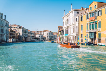 Motorboat floating on clear waters of Grand Canal in romantic Venice during bright summer daytime, landscape with ancient architecture buildings located in historic center of Italian city