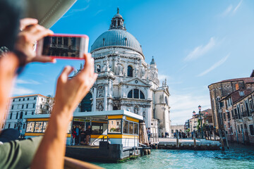 Cropped male tourist using smartphone technology for clicking pictures of santa maria della salute architecture during summer travelling to Venice, unrecognizable man shooting video vlog on cellular