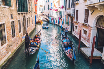 Venetian gondoliers carries tourists on gondola Grand Canal of Venice in romantic Italy, boat transportation and sightseeing excursion during daytime for exploring Venezian historic landscape