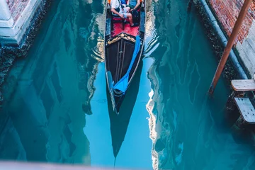 Tuinposter Veneziaanse gondel als taxivervoer voor een waterexcursie rond het stadsbeeld, boot voor het oversteken van het Canal Grande in de Italiaanse lagune - maak een romantische reis door de beroemde stad Venetië © BullRun