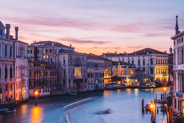 Filtred reflection of boat transport in Venecian gran Canal during evening time for romantic sightseeing on embankment around city, scenery view on ancient architecture buildings in Italy