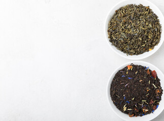 Dried fragrant black tea leaves with a wooden spoon on a light cement background.Composition with...