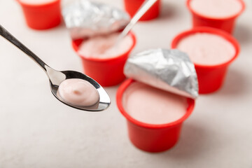strawberry yogurt in a red plastic cup with a spoon on a white background.