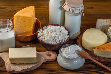 Bottles with milk, cheese, sour cream, butter on a wooden background. Farm organic fresh food. Dairy products