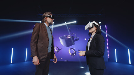 Two speakers in virtual reality glasses standing on the stage and talking about modern technologies...