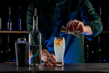 Bartender's hands serving cocktails on bar counter in a restaurant, pub. Mixed drinks. Alcoholic cooler beverage at nightclub on dark background