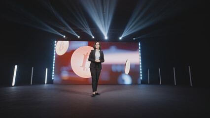 Female successful speaker on stage explaining to the audience investments and exchanges in front of...