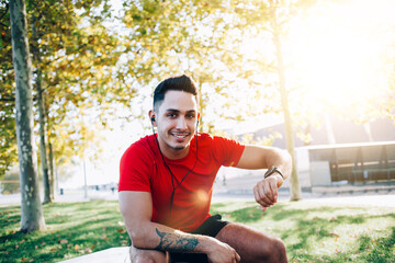 Portrait of happy muscular trainer man listening audio records via electronic headphones during...