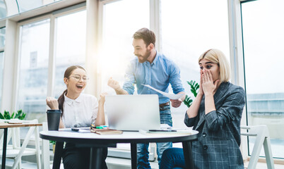 Colleagues celebrating success while working at laptop in office
