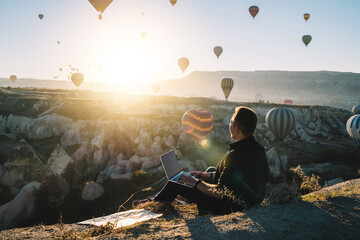 Male freelancer with laptop during hot air balloon festival